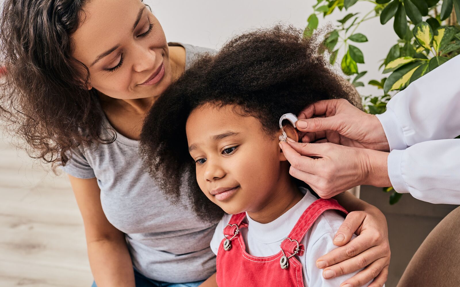Smiling deaf african american girl with ear implant at doctor's office.